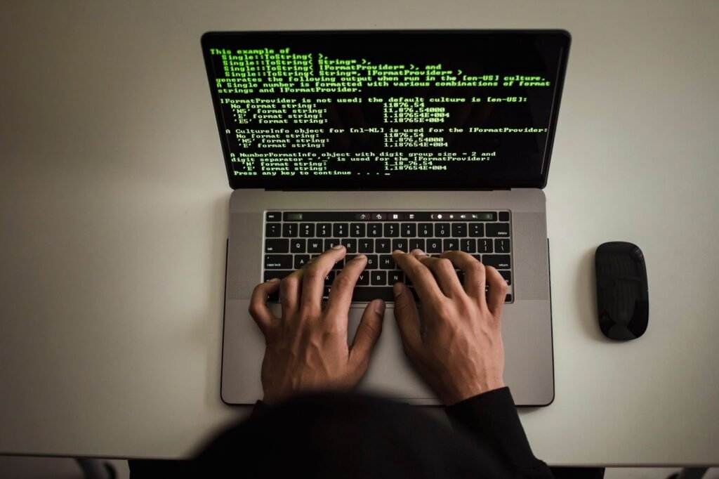 Hands typing code on a laptop with programming text on the screen