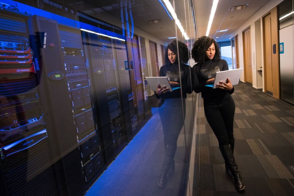 Engineer holding a laptop while walking between server racks in a data centre