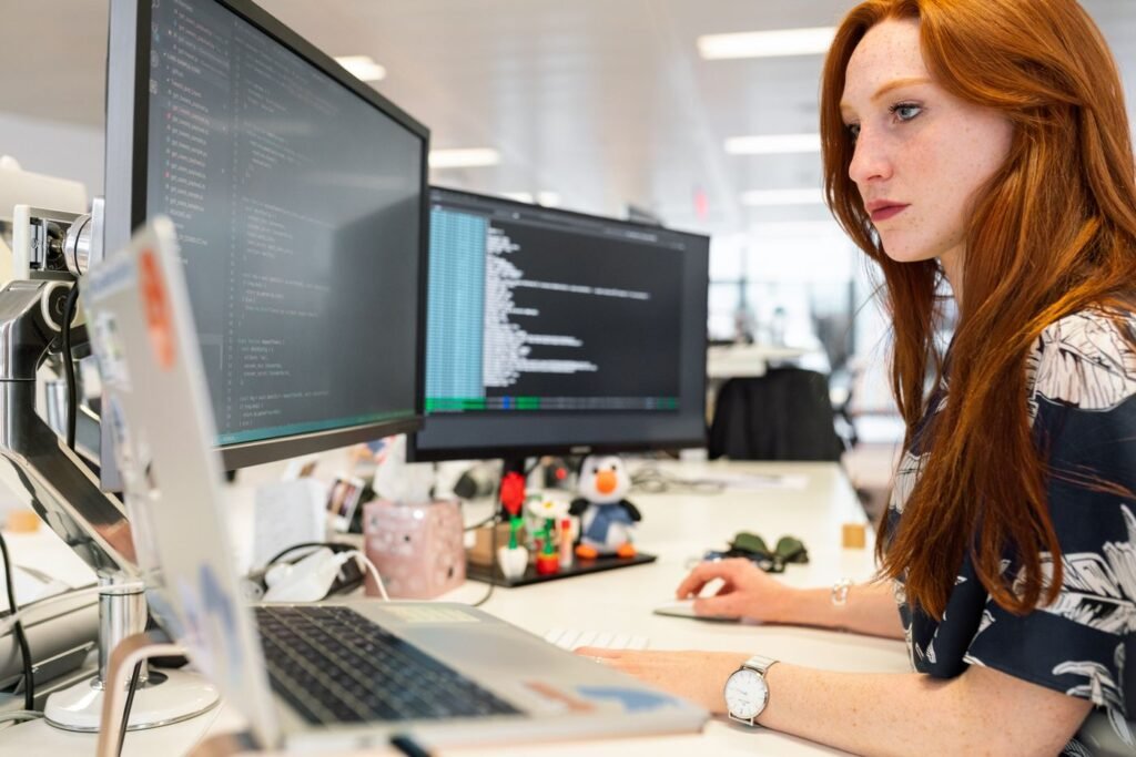Woman writing code on two monitors in an office
