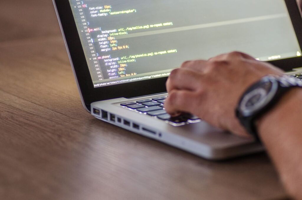Close-up of hands typing code on a laptop