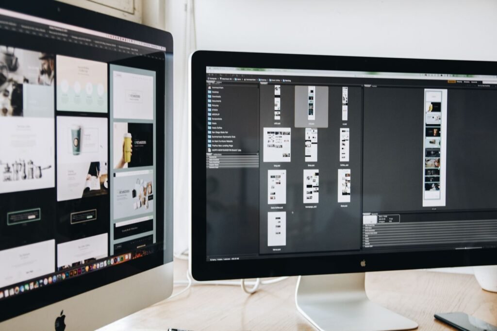Two computer monitors on a desk showing web design work