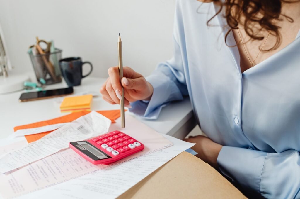 Woman calculating expenses with a calculator and papers at her desk