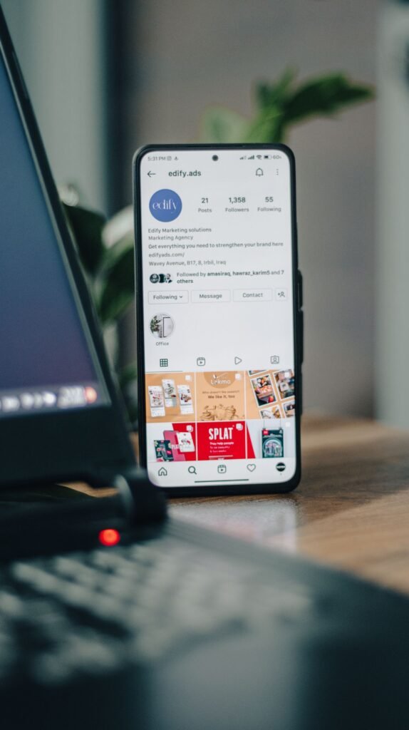 Phone showing a profile page next to a laptop on a table