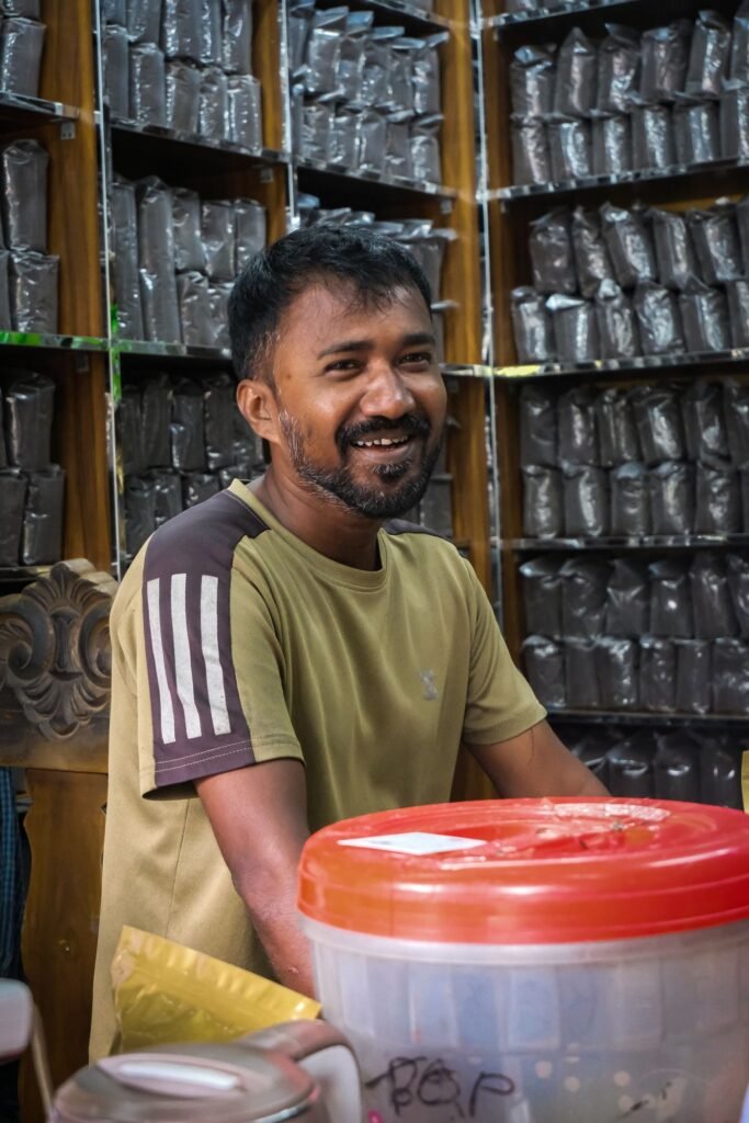 Smiling shopkeeper in a tea store stocked with packaged products