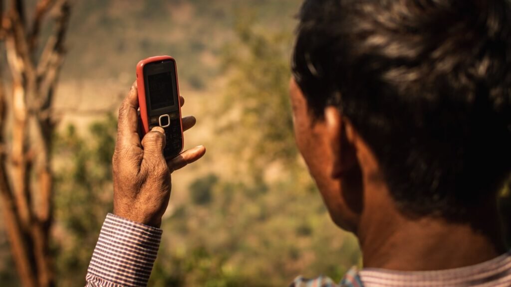 Man using a mobile phone outdoors in rural Odisha
