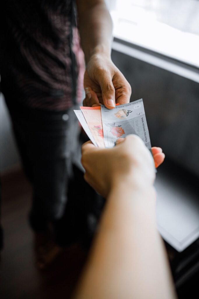 Close-up of one person handing banknotes to another indoors
