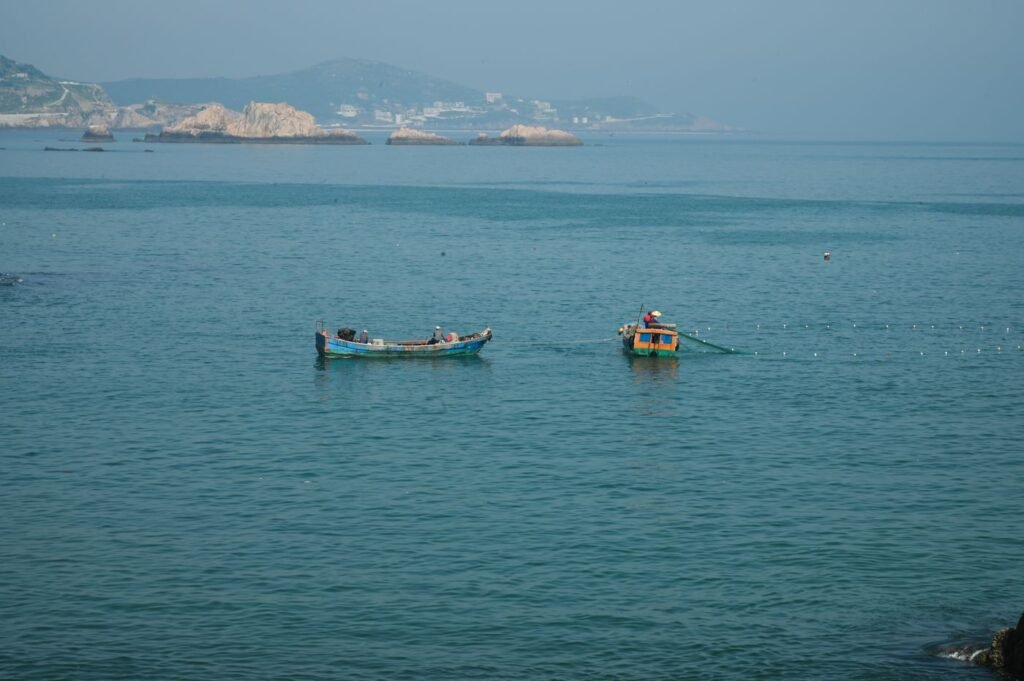 Fishing boats with nets cast on a calm blue sea near a distant coastline