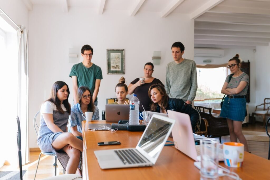 Group of young professionals gathered around a laptop in an office