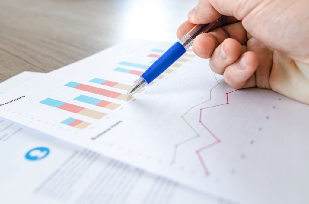 Hand holding a pen over printed bar and line charts