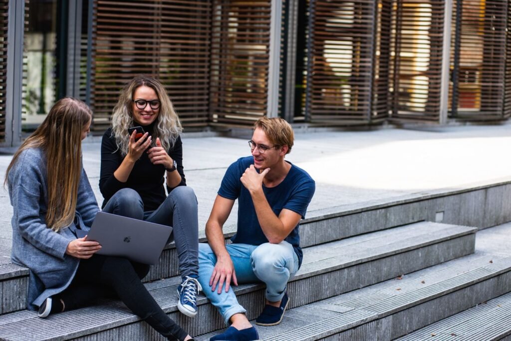 Three young people sitting on outdoor steps talking together