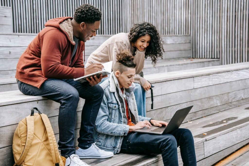 Group of students sharing a laptop while studying together on outdoor stairs