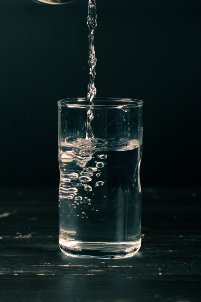 Clear water being poured into a drinking glass on a dark background