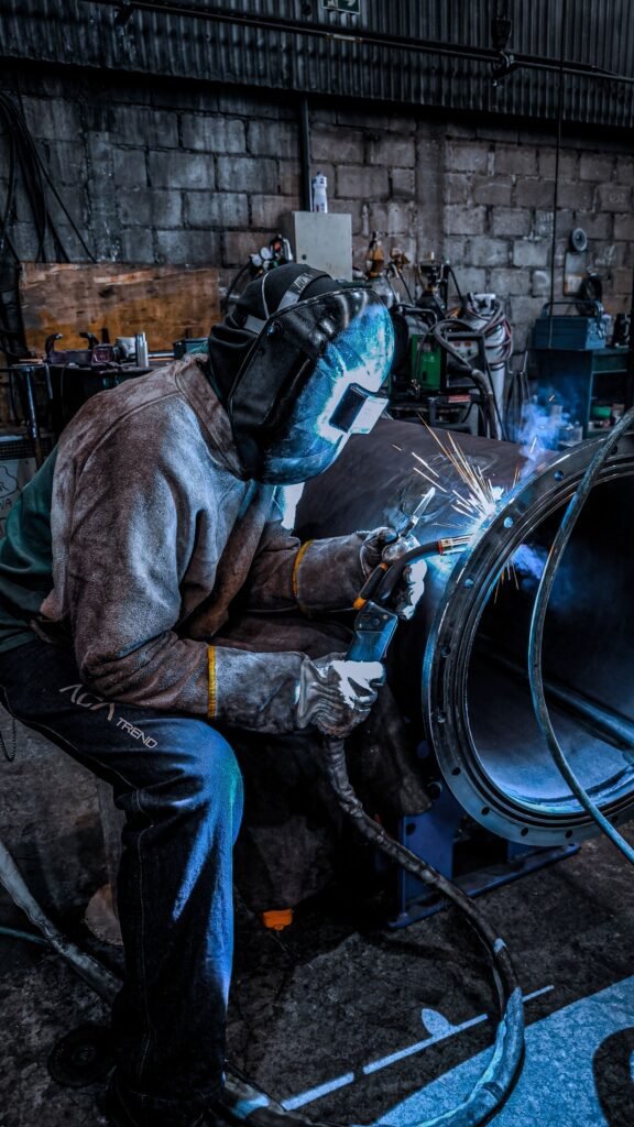 A worker in a helmet and safety gear welding inside a factory in Brazil