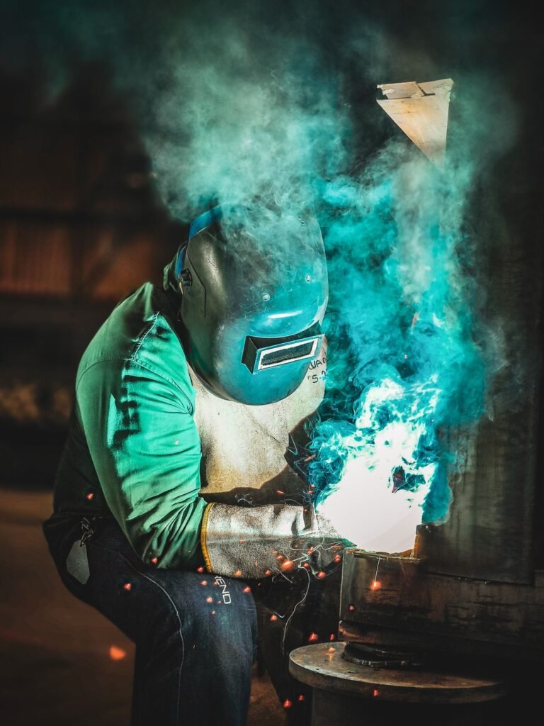 A worker welding metal inside a small workshop with bright sparks