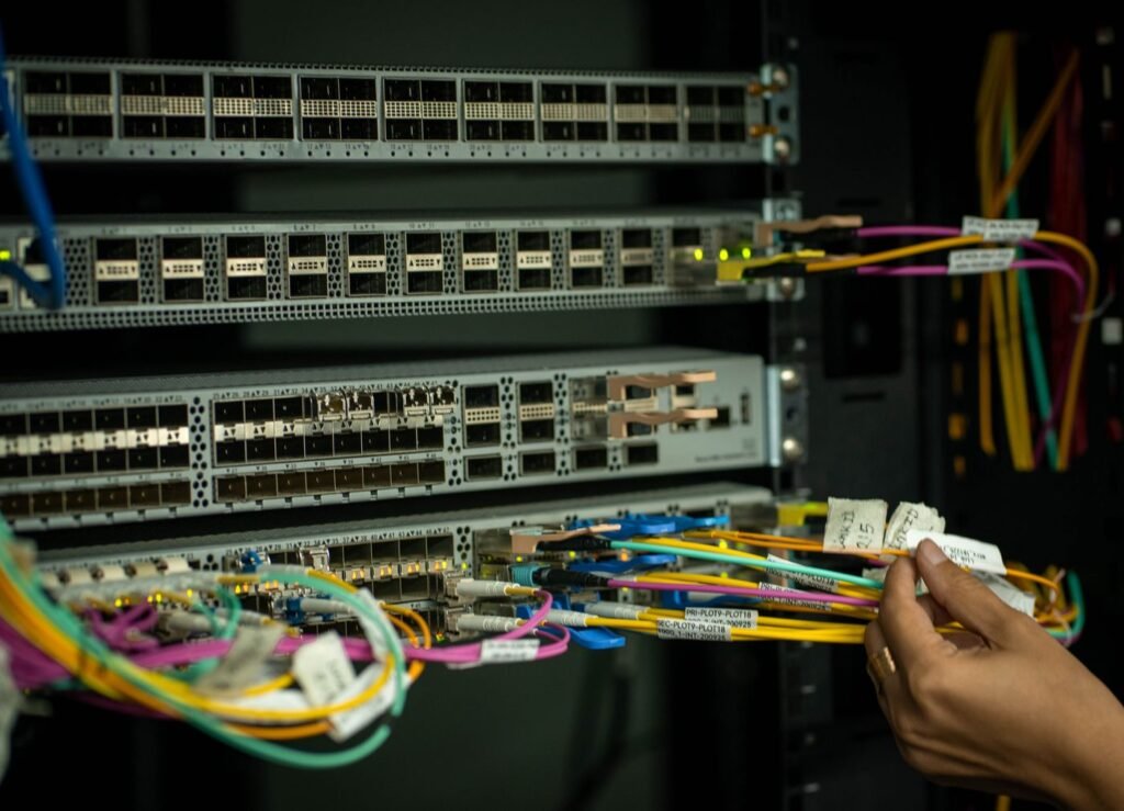 A hand handling fibre optic cables in a server room