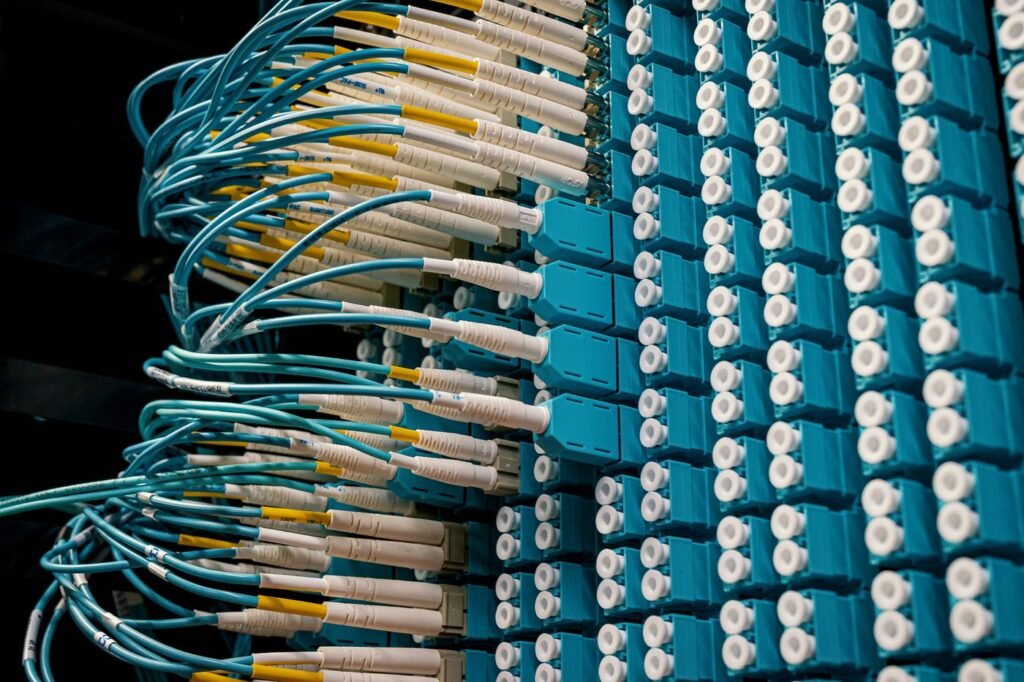 Fibre optic patch cables plugged into a blue patch panel in a data centre