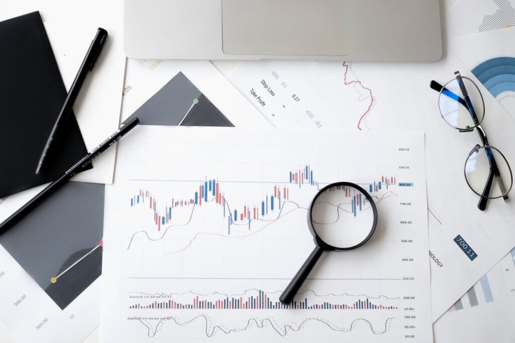 Magnifying glass resting on analysis papers beside pens and glasses
