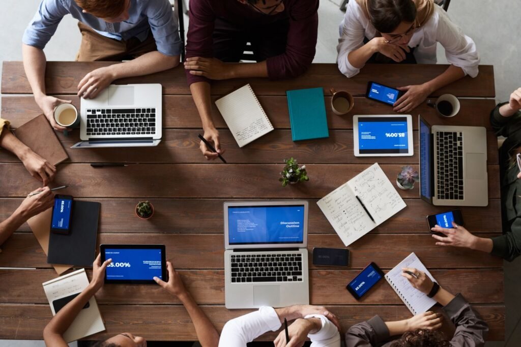 Overhead view of a team around a wooden table with laptops and tablets