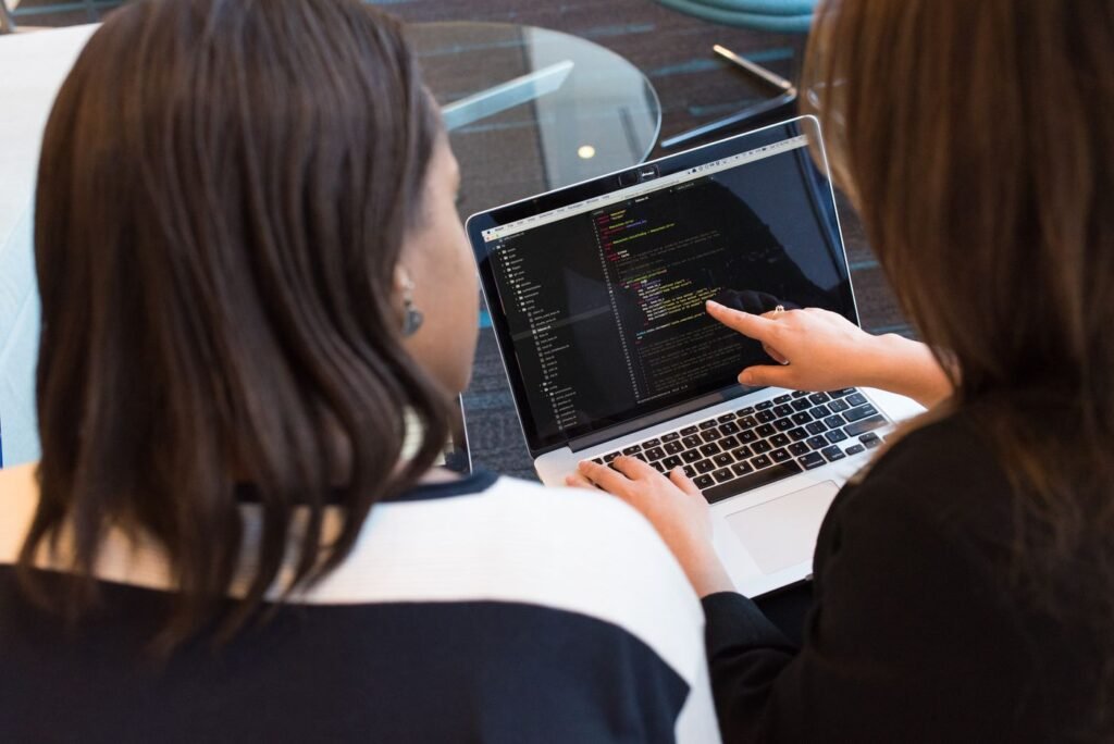 Two women looking at code together on a laptop
