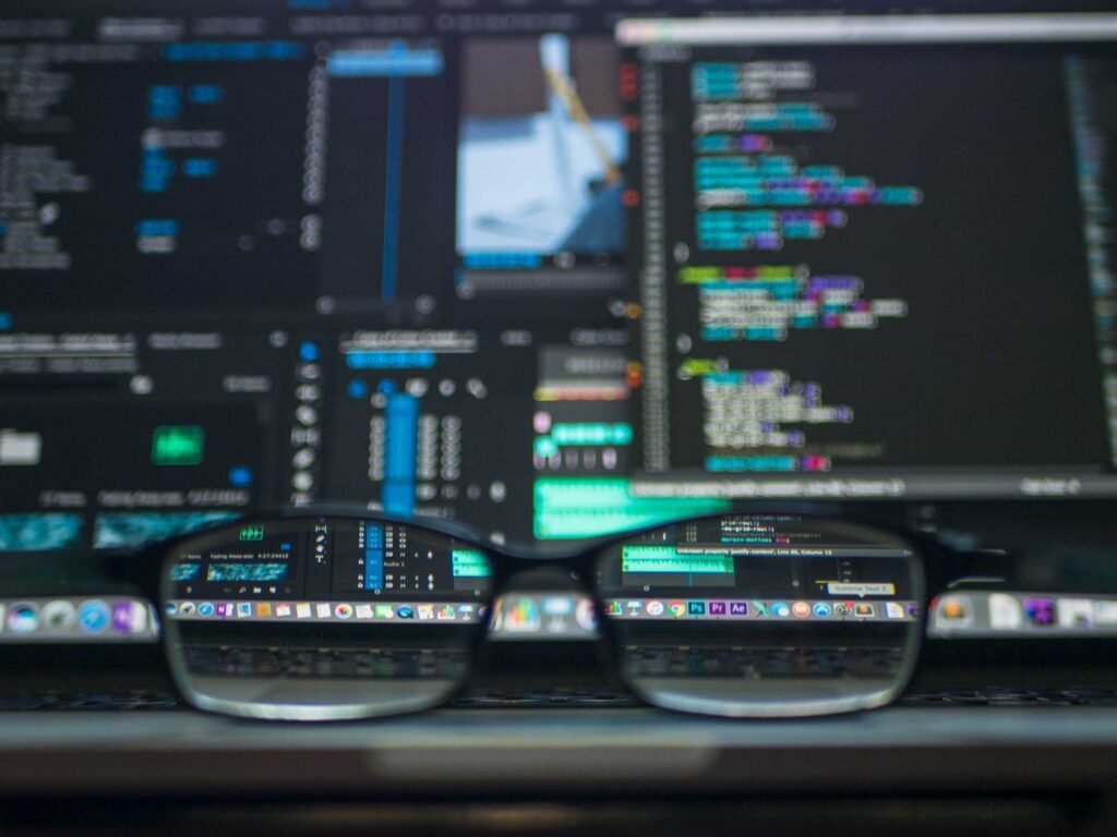 Lines of code reflected in a pair of glasses in front of a screen