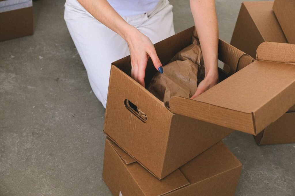 Person packing belongings into a cardboard box before a move