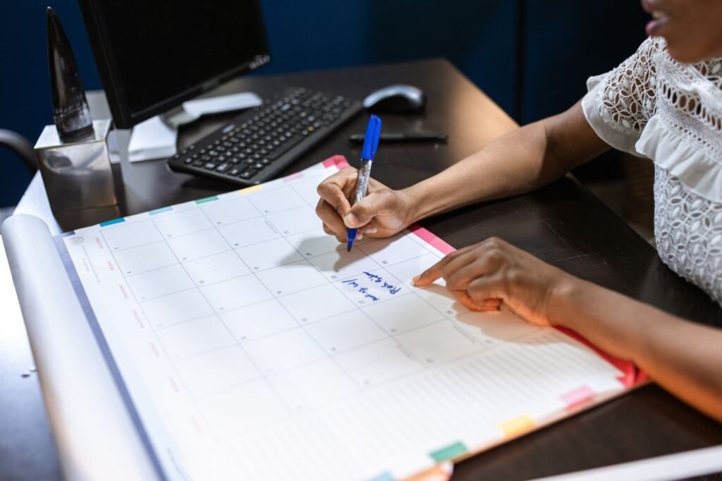 Person writing tasks on a wall calendar